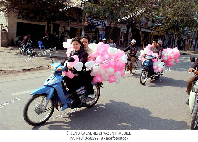 Traders with pink and white balloons drive through a shopping street in Hanoi, capital city of Socialist Republic of Vietnam (Photo from December 2004)