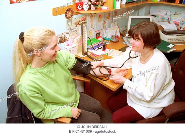 Female doctor taking patient's blood pressure in GP surgery