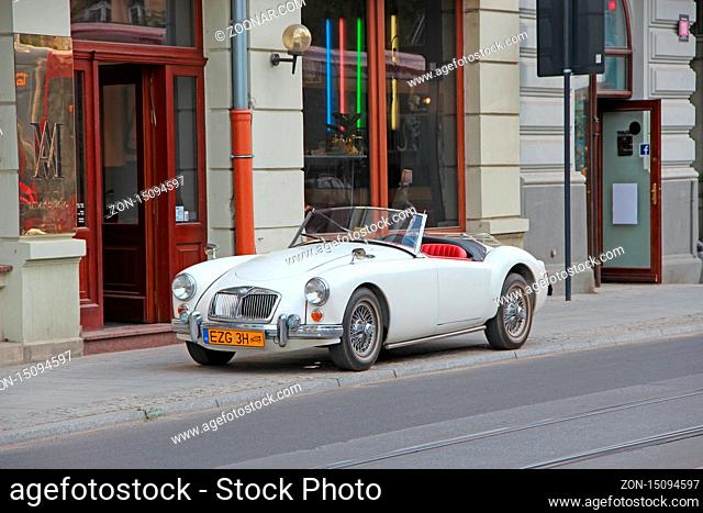 MG car cabriolet on street of Lodz. White auto MG cabriolet standing on curb of city road in Lodz. White 1960 MG MGA convertible roadster parked on city road