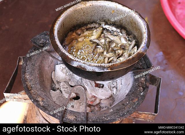 A pot with small fish is seen on a charcoal stove. Small fish is often eaten fried. Malingunde, Malawi