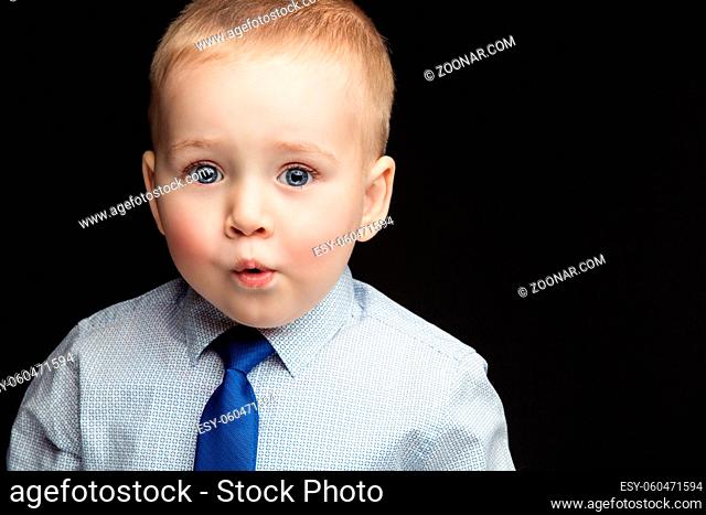 Handsome funny little boy wearing shirt and blue tie with expression of surprise on face. True emotions. Studio shot. Horizontal. Copy space