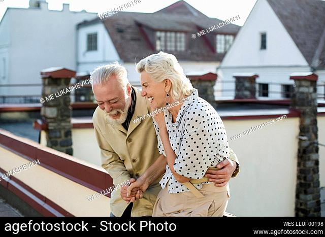 Couple laughing while sitting on retaining wall