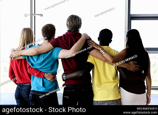 Business colleagues standing arms around in office