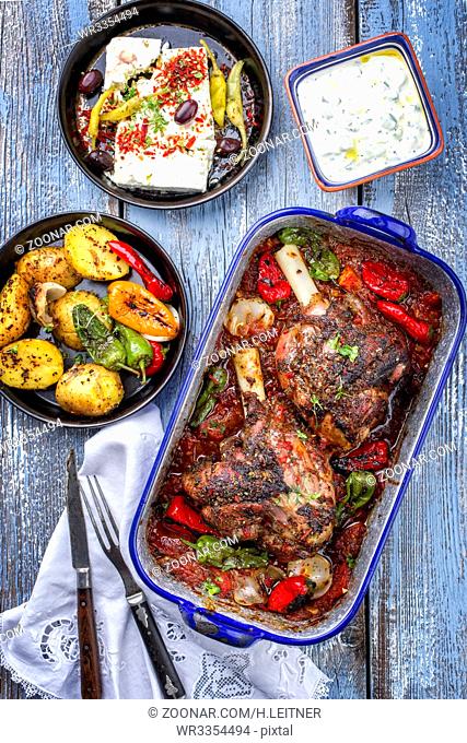 Greek roasted leg of lamb with feta and potatoes in tomato sauce as top view in a skillet