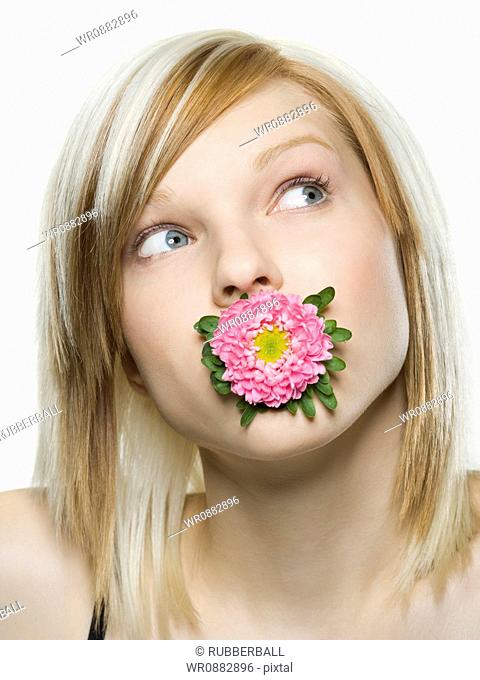 Close-up of a young woman holding a flower in her mouth