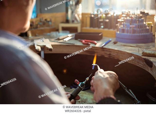 Craftswoman using blow torch in workshop
