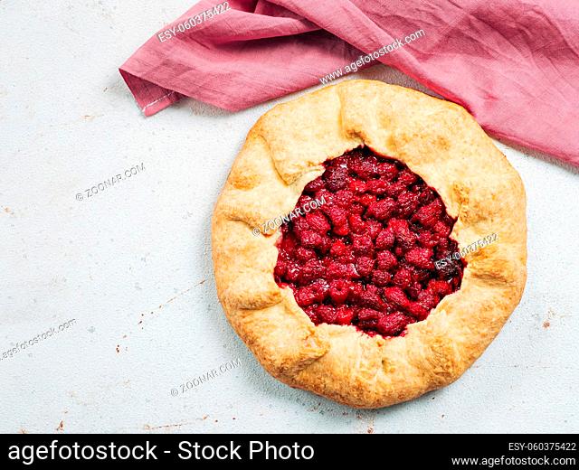 Perfect raspberry galette. Delicious rustic homemade tart with frozen or fresh raspberries on white textured background. Beautiful round shape galette with...