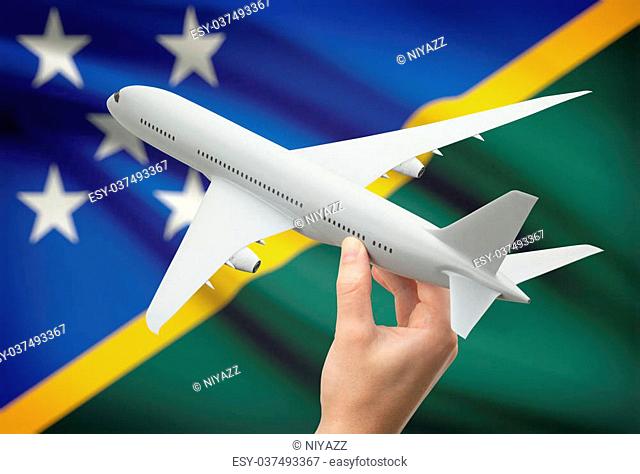 Airplane in hand with national flag on background - Solomon Islands