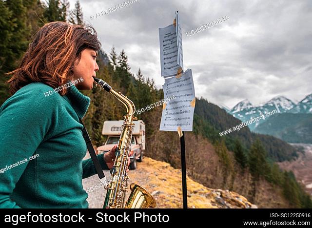 Woman standing on a mountain in the Squamish Valley, British Columbia, Canada, playing the saxophone