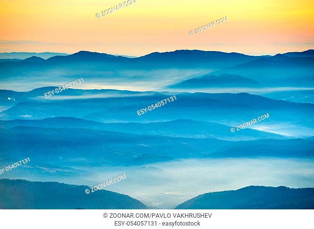 Blue mountains and hills under beautiful orange sunset