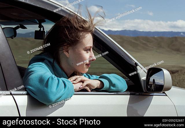 The European girl goes in the car having put out the head in a window