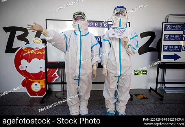29 January 2022, China, Peking: Helpers in full protective gear stand at Beijing airport to welcome athletes, delegations and journalists arriving on special...