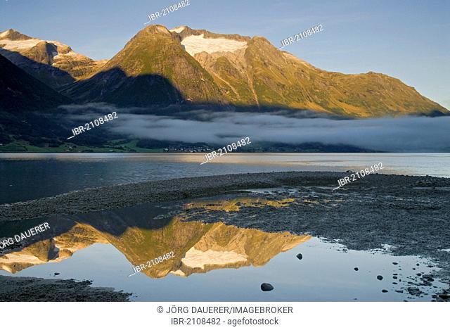 Morning fog over Strynevatnet, surrounded by mountains, reflected in a small puddle, as seen from Hjelle, Loen, Sogn og Fjordane, Norway, Europe