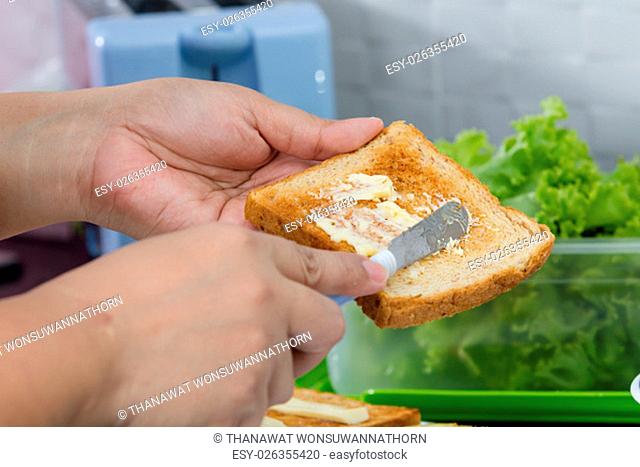 women hand spreading butter on toast