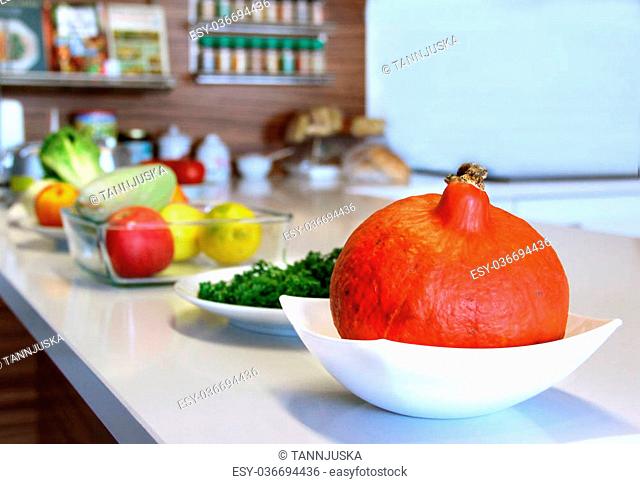 Well designed modern kitchen with a big variation of ripe fruit and vegetables on the table