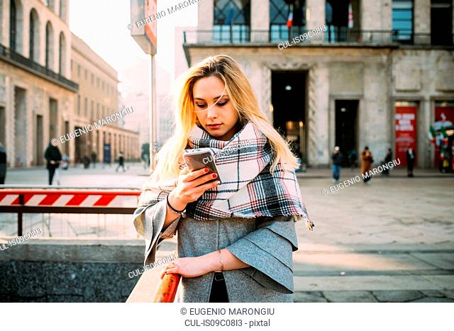 Young woman looking at smartphone on city street