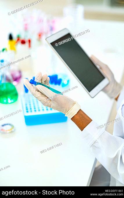 Researcher holding test tube and digital tablet in laboratory