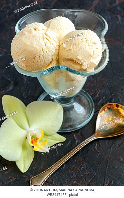 Artisanal vanilla ice cream in a glass vase on a dark concrete table