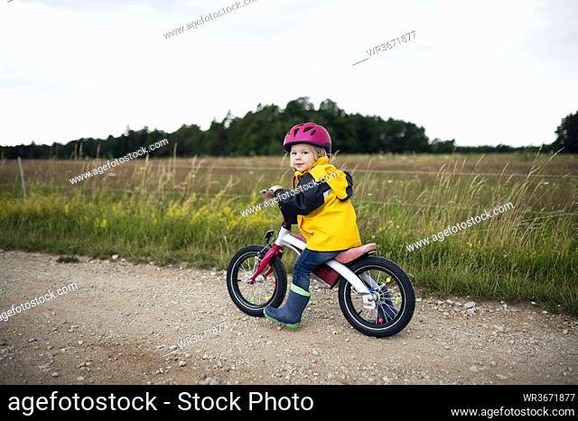 Toddler girl with pink cycling helmet on balance bicycle