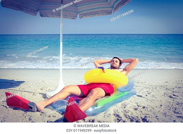 Man lying on the beach with flippers and rubber ring