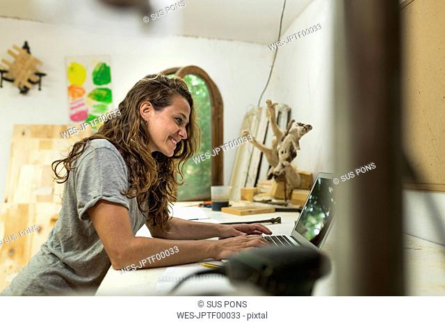 Craftswoman using laptop at her desk