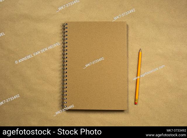Brown notebook and classic pencil on brown plain paper background texture, copy space or space for text, business or education concept top view modern retro...