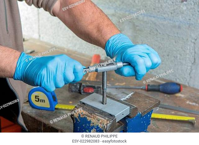 a man with blue gloves tapped a metal part