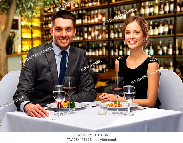 smiling couple with food and wine at restaurant