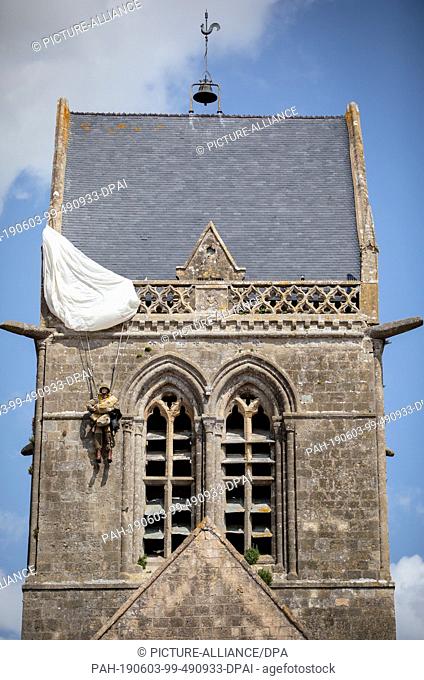 03 June 2019, France (France), Sainte Mere Eglise: A skydiving doll hangs on the church of Sainte Mere Eglise. On 06.06.1944 about 14000 allied paratroopers of...