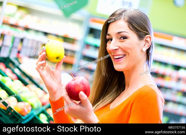 Woman selecting apples while grocery shopping in supermarket