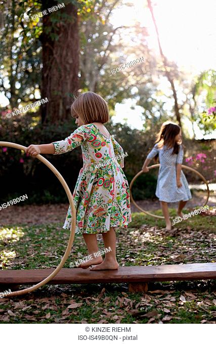 Sisters playing with plastic hoops in shaded garden