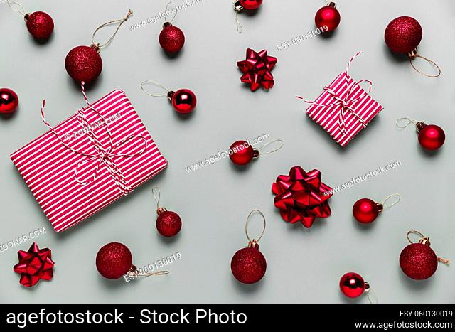 Gray background with two pink Christmas gift box presents, small red Christmas balls or sphere toys, ribbon bows for fir tree