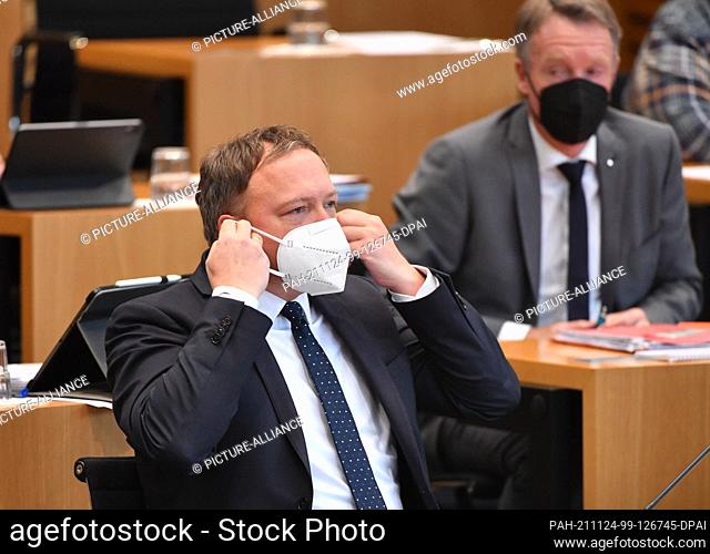 24 November 2021, Thuringia, Erfurt: Mario Voigt, CDU faction leader, puts on his mask in a special session of the Thuringian state parliament on the Corona...