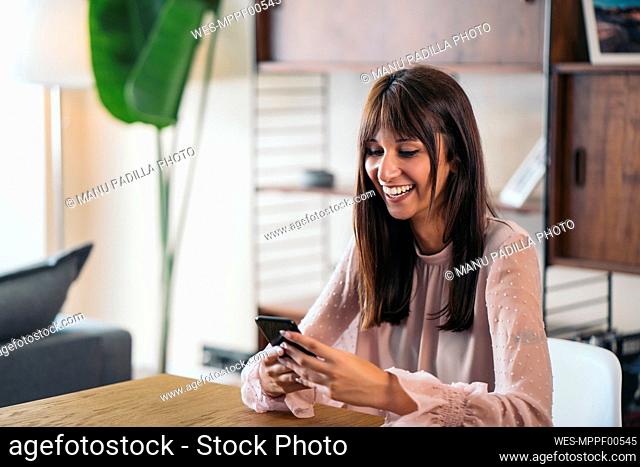 Happy young woman using cell phone at home