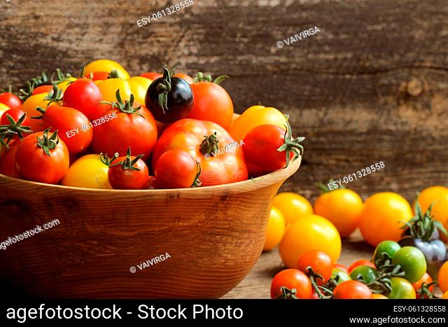 Wooden bowl with fresh vine ripened heirloom tomatoes from farmers market