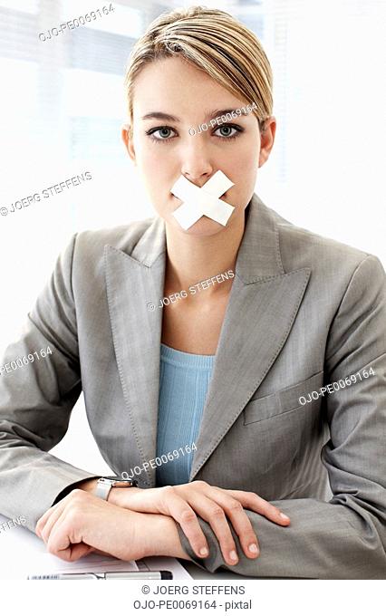 Businesswoman with tape covering mouth