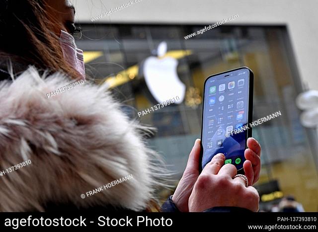 Mask compulsory in the pedestrian zones and public places in Munich on 11.11.2020. Young woman with everyday mask looks at her Apple Iphone 12 PRO-in the...