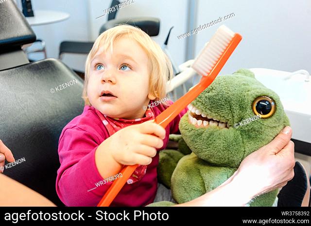 Child at the dentist brushing teeth of a plush toy learning how to do it