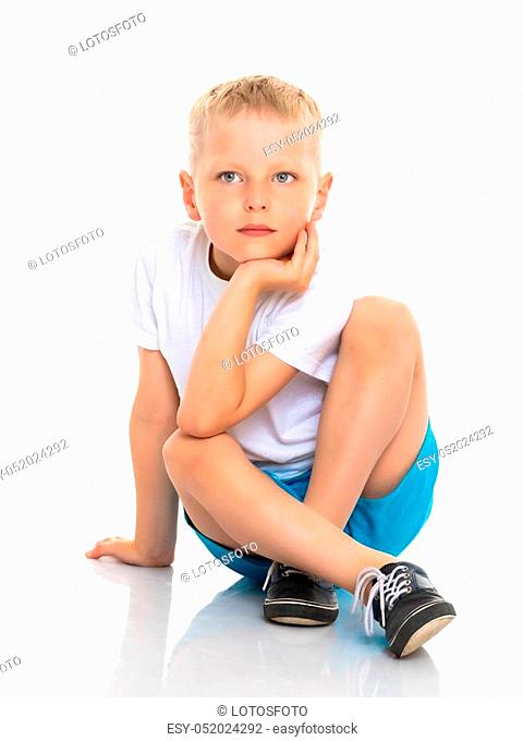 Cute little boy is sitting on the floor on a white background. The concept of a happy childhood, the harmonious development of the child in the family