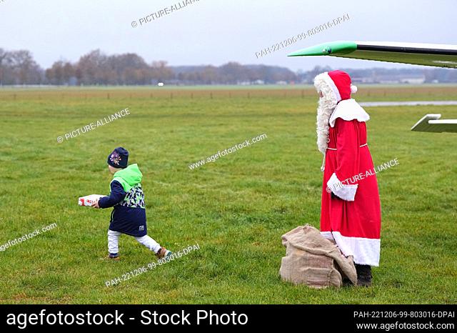 06 December 2022, Brandenburg, Paulinenaue: A man costumed as Santa Claus stood in front of the airplane after his arrival at the airfield Bienenfarm and gave...