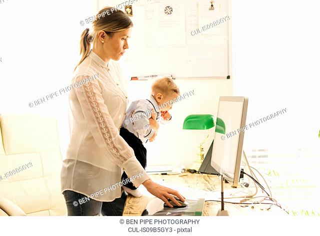 Mother working and caring for baby at home