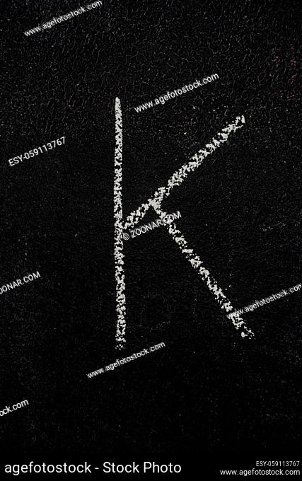 Letter K drawn with white chalk on blackboard. Education, school concept