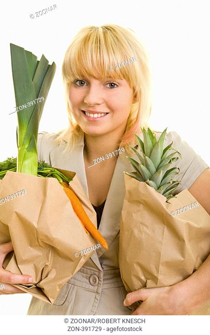 Junge Frau trägt zwei Papiertüten mit Obst und Gemüse