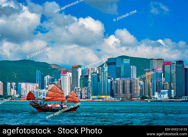 HONG KONG, CHINA - MAY 1, 2018: Hong Kong skyline cityscape downtown skyscrapers over Victoria Harbour in the evening with junk tourist ferry boat on sunset