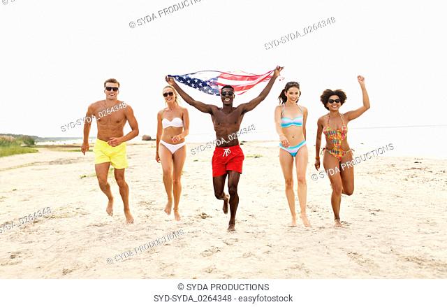 happy friends with american flag on summer beach