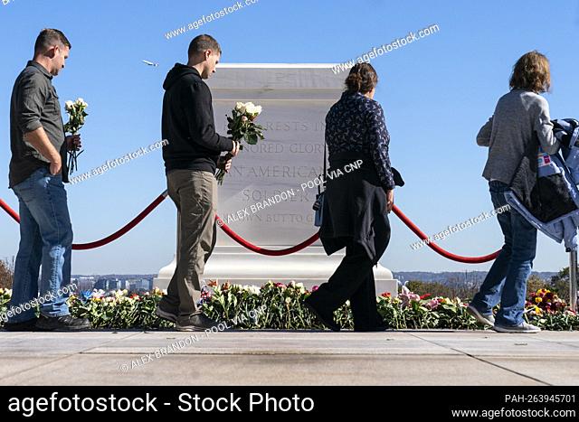People walk to place flowers during a centennial commemoration event at the Tomb of the Unknown Soldier, in Arlington National Cemetery, Tuesday, Nov