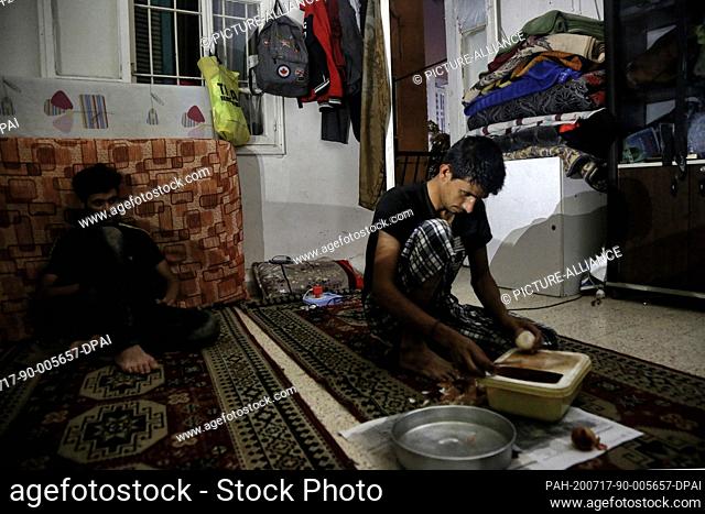 16 July 2020, Lebanon, Beirut: Two men sit inside an apartment lightened with their mobile phone torch during a blackout that sometimes lasts for 22 hours per...