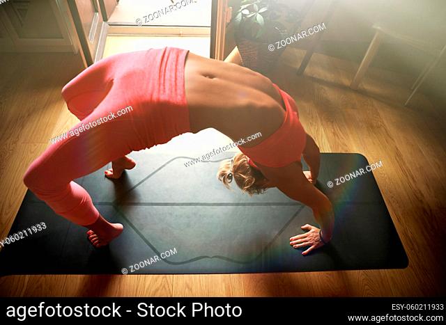 Young woman doing morning yoga in the home, using laptop cor yoga online. High quality photo