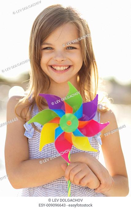 summer holidays, celebration, family, children and people concept - happy girl with colorful pinwheel toy