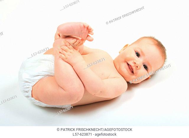 Baby lying on back, wearing nappies, playing with its feet, Studio, Oetwil am See, Zuerich, Switzerland